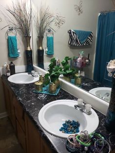 two sinks in a bathroom with blue towels on the wall and zebra print shower curtain