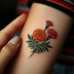 a woman's arm with an orange flower tattoo on it