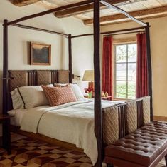 a bedroom with a four poster bed and red curtains