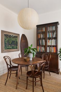 a dining room table and chairs with bookshelf in the background