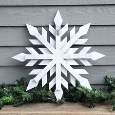 a snowflake made out of wood sitting on top of a wooden table next to evergreens