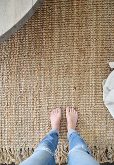 a person is standing on the floor with their feet propped up in front of a rug