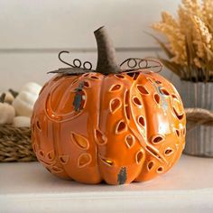 an orange carved pumpkin sitting on top of a table next to some plants and other decorations