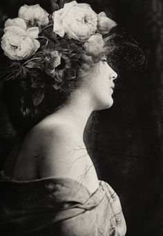 black and white photograph of a woman with flowers in her hair, looking off to the side