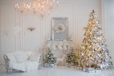 a living room decorated for christmas with white and silver decorations on the walls, a fireplace, and a chandelier