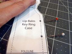 a person cutting out a pattern for a dress with pins on the bottom and side