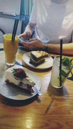 a person sitting at a table with plates of food and drinks in front of them