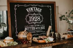 an old fashioned sign is on the wall above a table full of cheeses and grapes