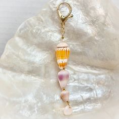 a pink, yellow and white glass bead hanging from a gold plated keychain