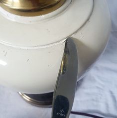 a close up of a white lamp with a gold plate on it and a silver spoon next to it