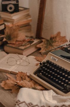 an old fashioned typewriter sitting on top of a table next to books and glasses