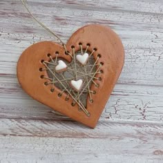 a heart shaped ornament hanging from a string on a wooden table with white paint