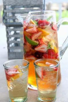 pitcher and two glasses filled with fruit on top of a table next to each other