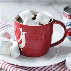 a red cup filled with marshmallows on top of a white plate