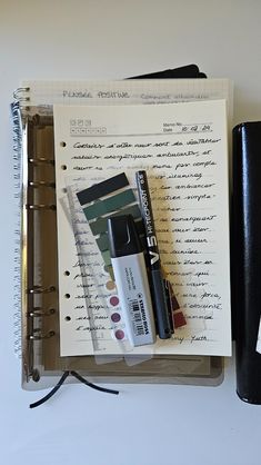 an open notebook with pens and other items on it