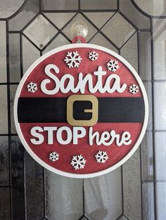 a santa sign hanging from the side of a glass door with snowflakes on it