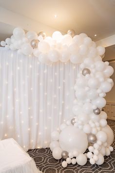 a balloon arch in the middle of a room with white and silver balloons on it