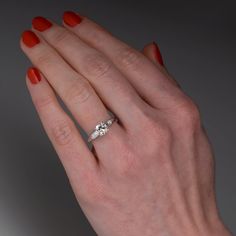 a woman's hand with an orange manicured nail polish holding a diamond ring