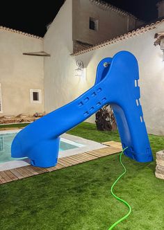 an inflatable water slide next to a swimming pool with grass on the ground