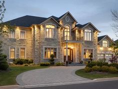 a large house with lots of windows and lights on it's front door is lit up at night