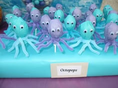 there are many octopus cupcakes on the blue cake plate with purple icing