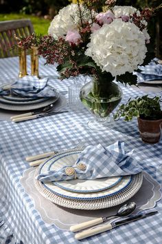 the table is set with plates, silverware and flowers in vases on it