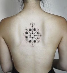 the back of a woman's neck with an intricate tattoo design on her left shoulder