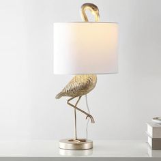 a table lamp with a gold bird on it and a white shade over the base