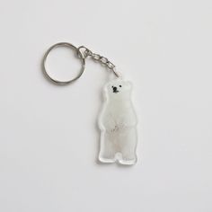 a white keychain with a polar bear on it's front and back sides