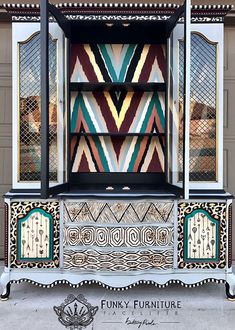 an ornately decorated cabinet with glass doors on the front and sides, painted in multi - colored geometric patterns