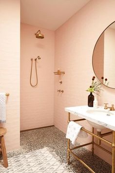 a bathroom with pink walls and flooring has a mirror, sink, shower, and stool