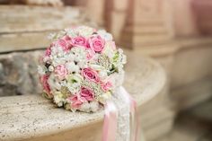 a bridal bouquet sitting on top of a stone bench