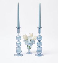 two blue glass candlesticks with flowers in the middle and one candle holder on each side