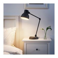 a white nightstand with a black lamp and flowers on it next to a night stand