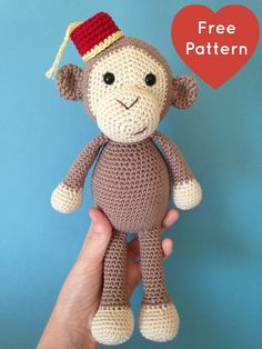 a crocheted monkey with a red hat on it's head is held in front of a blue background