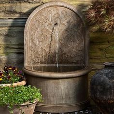 a water fountain sitting next to some potted plants