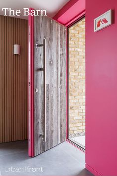 an open door in a pink room next to a brick wall with the words the barn on it