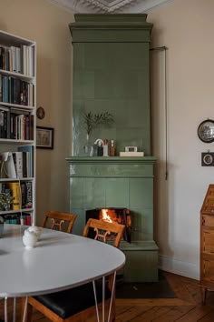 a room with a table, bookshelf and fire place in the fireplace area