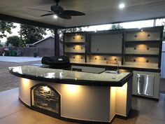 an outdoor kitchen with built in cabinets and lighting