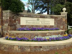 the entrance sign to providence arbours is surrounded by flowers and stone steps that lead up to it