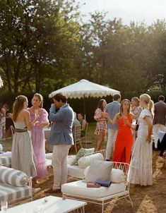 a group of people standing around each other in front of a tent and couches