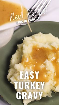 a green plate topped with mashed potatoes covered in gravy next to a fork