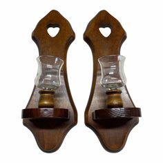 two wooden wall sconces with glass holders on each one and a wood handle