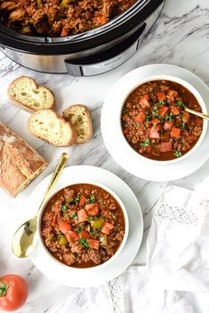 two bowls of chili with bread on the side