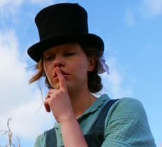 a woman wearing a top hat and holding her finger to her lips