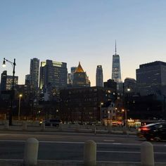 the city skyline is lit up at night, with cars driving down the street in front of it