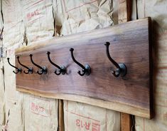 a wooden coat rack with five hooks on it and some bags in the back ground