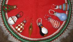 christmas ornaments are arranged in a circle on a red tablecloth with white fringes