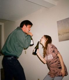 a man standing next to a woman holding a wine bottle in her hand while she is drinking