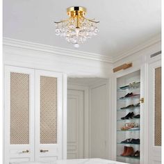 a white bed sitting under a crystal chandelier in a bedroom next to closets